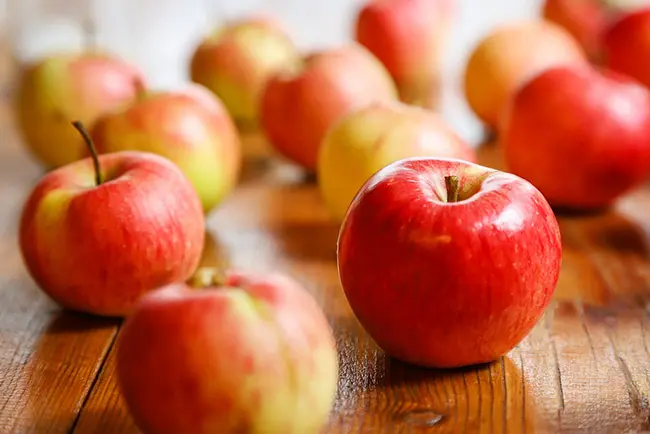 나무 테이블에 많은 사과를 정신없이 올려 놓은 모습